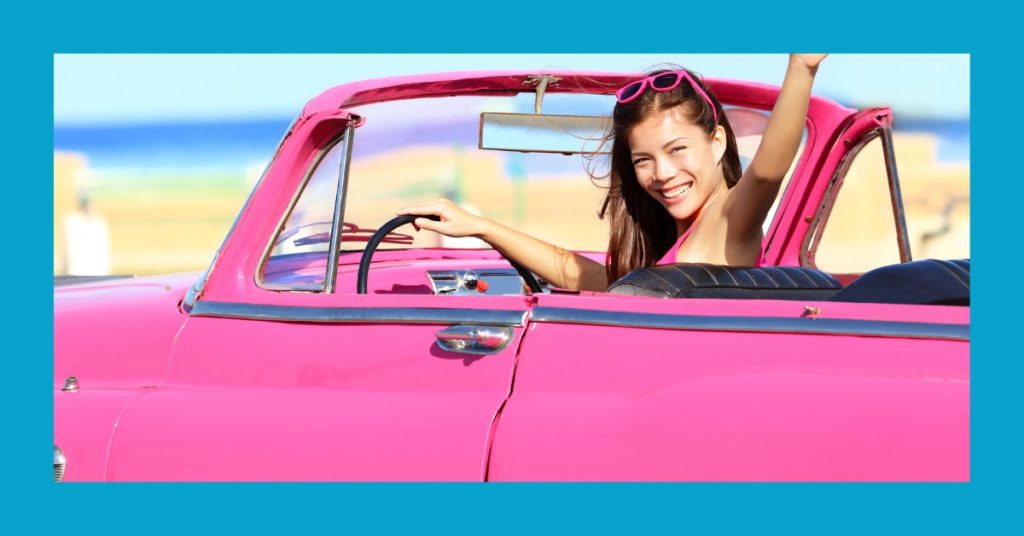 Young woman waving from convertible